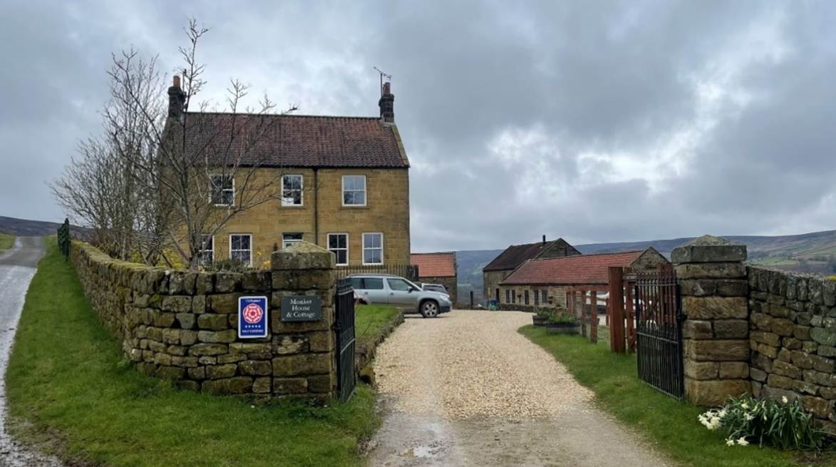 A dirt road leading to a stone wall
Description automatically generated